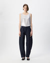 full body image of model wearing denim barrel leg pants and silver shell top