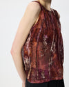 A sleeveless sheer top with an abstract vertical pattern in deep burgundy, brown, and purple tones, shown on a model against a plain white background.
