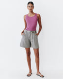 Woman wearing a pink tank top and grey shorts on a white background