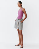 Woman wearing a pink tank top and grey shorts on a white background