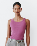 Woman wearing a pink tank top and grey shorts on a white background