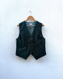 Dark green vest on a wooden hanger against a white background