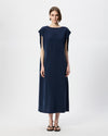 A woman modeling a navy blue midi dress with cap sleeves, paired with black sandals, against a plain light gray studio background.
