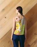 Model wears spliced patchwork top against wooden background