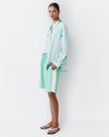 Model wears teal shorts with light lemon yellow racing stripe down the sides of the shorts.