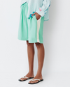 Model wears teal shorts with light yellow racing stripe down the side