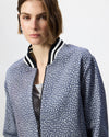 A close-up of a model wearing a blue and white patterned bomber jacket with a striped black and white ribbed collar.