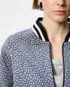 Close-up of a model wearing a blue and white patterned bomber jacket with a black and white striped ribbed collar.