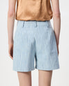 A person shown from the back wearing light blue textured shorts and a tan sleeveless top against a plain light background.