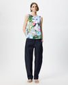 A model stands against a light gray studio background wearing a sleeveless top with a colorful floral print and dark navy wide-leg trousers.