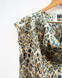 Leopard print top on a hanger with a white background