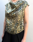 Person wearing a sleeveless top with a leopard print pattern against a plain background