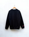 the back of a black sweatshirt hanging against a white wall