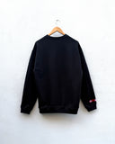 the back of a black sweatshirt hanging against a white wall
