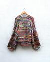multicoloured handknitted cardigan hanging on white wall