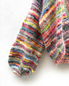 multicoloured handknitted cardigan hanging on white wall
