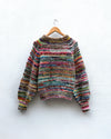 handknitted colourful jumper hanging on a wall