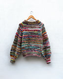 handknitted colourful jumper hanging on a wall