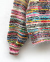 handknitted colourful jumper hanging on a wall