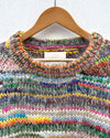 handknitted colourful jumper hanging on a wall