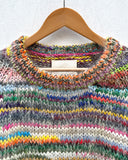 handknitted colourful jumper hanging on a wall