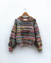 handknitted colourful jumper hanging on a wall