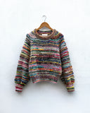 handknitted colourful jumper hanging on a wall