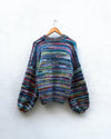 multicoloured handknitted cardigan hanging on a wall
