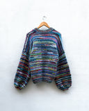 multicoloured handknitted cardigan hanging on a wall
