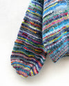 multicoloured handknitted cardigan hanging on a wall