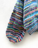 multicoloured handknitted cardigan hanging on a wall