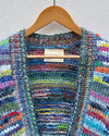 multicoloured handknitted cardigan hanging on a wall