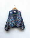 multicoloured handknitted cardigan hanging on a wall