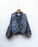 multicoloured handknitted cardigan hanging on a wall