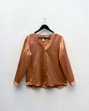 Nectar blouse on a hanger against a white wall