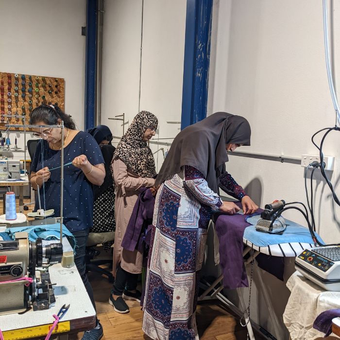 a group of women pressing their work as part of the earn and learn sewing program