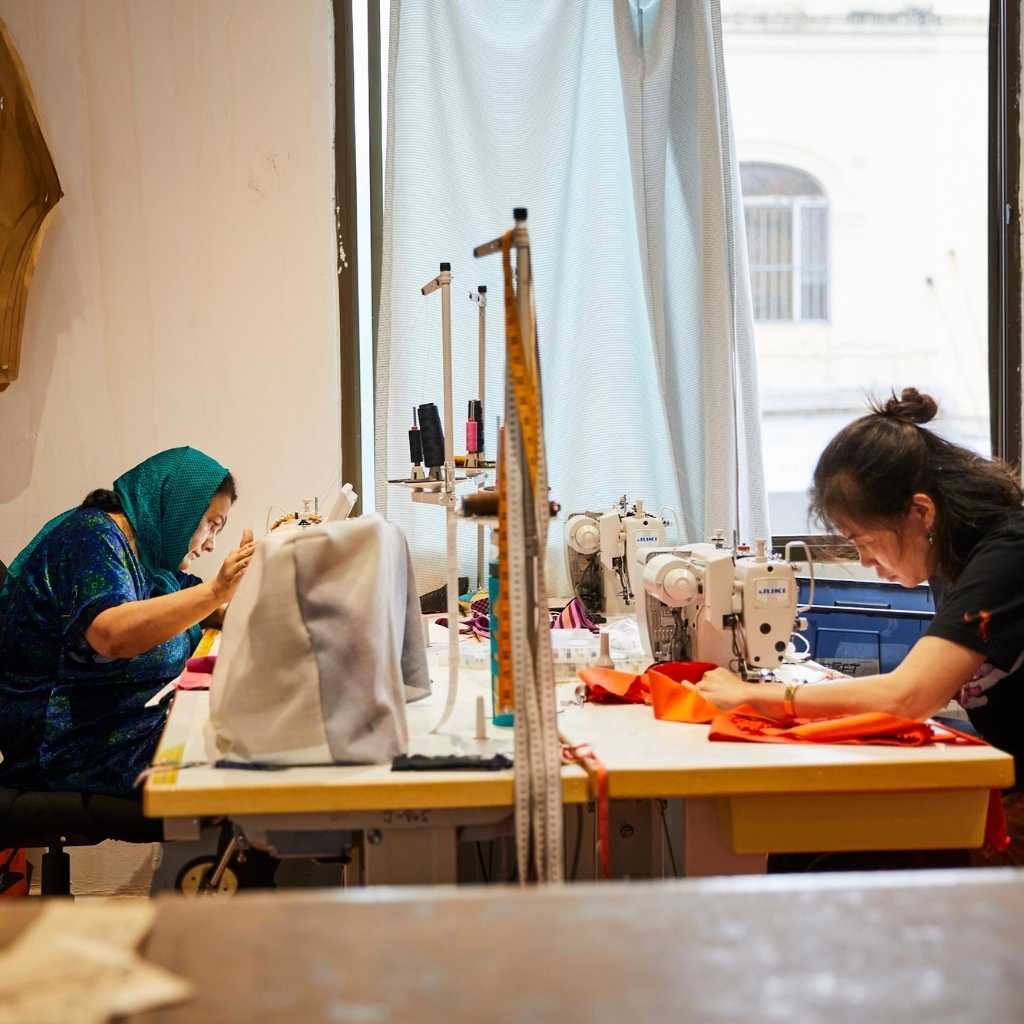 two women from refugee and new migrant backgrounds sewing in The Social Outfit's Newtown-based workroom manufacturing ethically made garments for third party clients in Sydney, Australia.