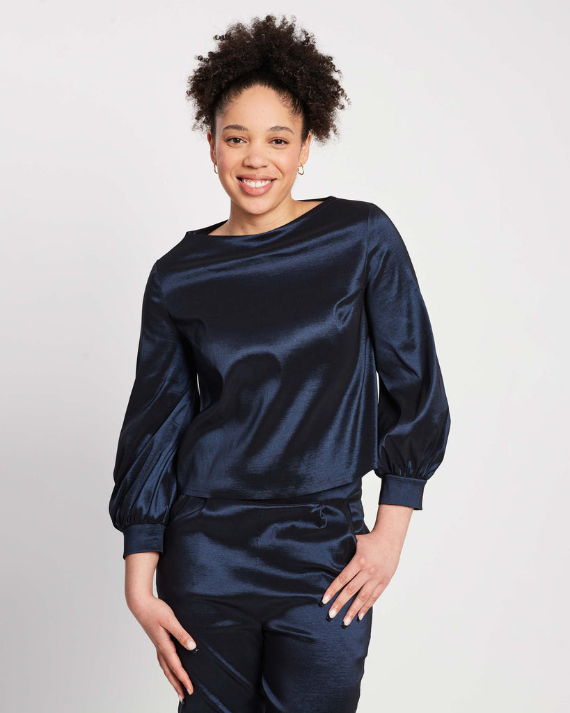 woman wearing navy bishop sleeve top with voluminous sleeves and cuff, with matching straight leg navy pants