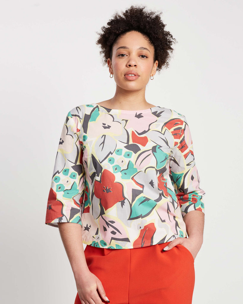 woman wearing colourful 3 quarter sleeve top with green and red on top of orange crepe pants