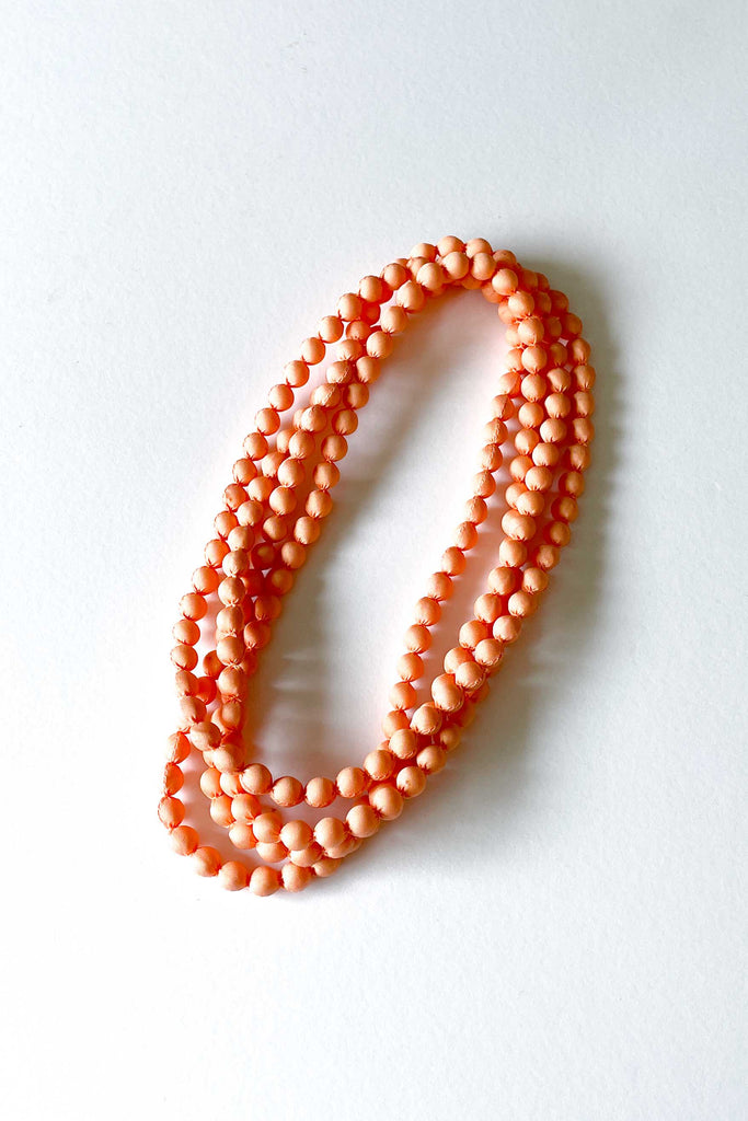 peach silk long strand necklace by tabitha cambodia against white backdrop