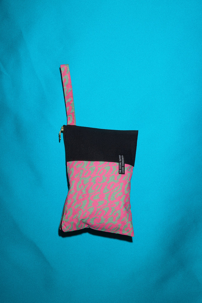 clutch bag with printed material and fabric strap against a blue backdrop