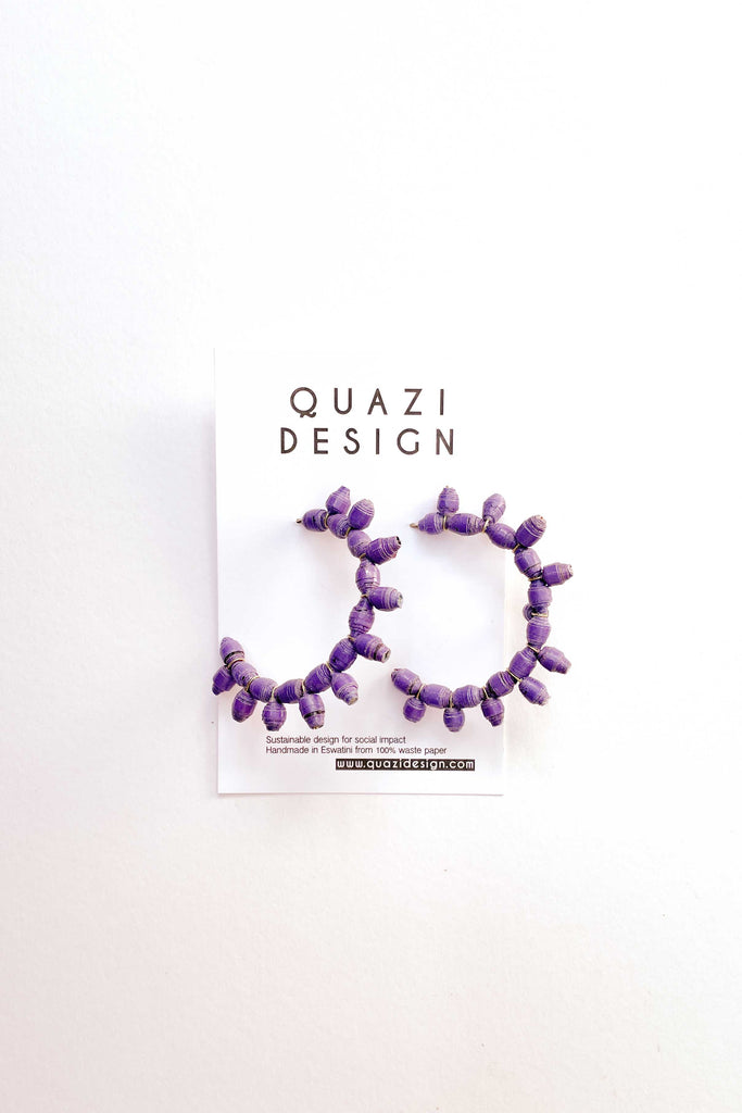 pair of purple sun earrings by quazi design against white backdrop
