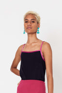 person with blond short hair wearing pink bind silk camisole on top and pink skirt against white backdrop