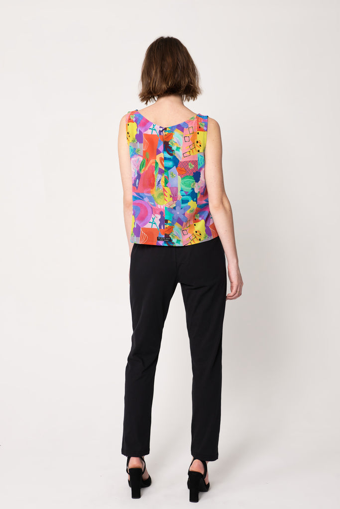 woman wearing blue and pink silk printed sleeveless shell top over black straight leg pants